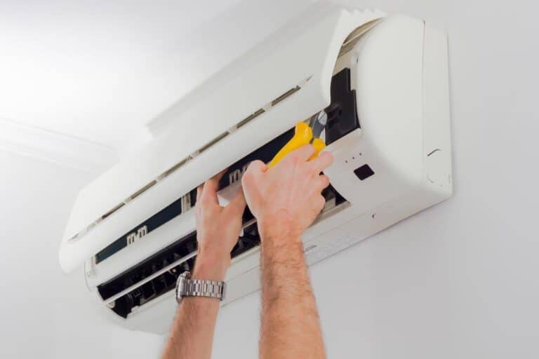 Man Inspecting An Air Conditioning Unit For Maintenance