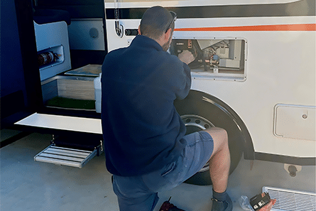 A Man Kneels by An RV, Ready to Fix the Door with Tools in Hand — Air-Conditioning and Refrigeration in Sunshine Coast, QLD