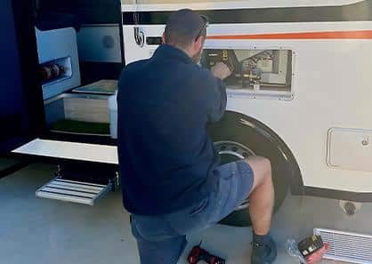 A Man Kneels by An RV, Ready to Fix the Door with Tools in Hand — Air-Conditioning and Refrigeration in Sunshine Coast, QLD